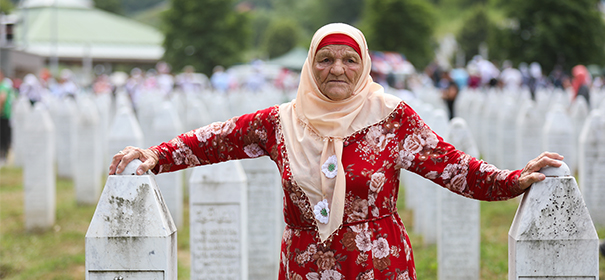 Eine Frau vor dem Grab ihrer Familienmitglieder in Srebrenica