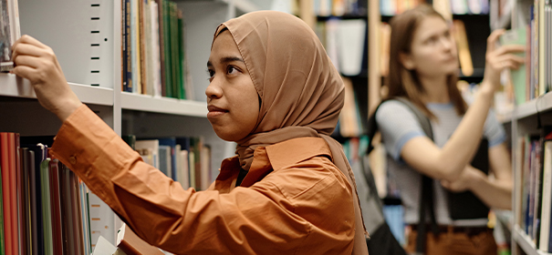Muslimische Frau mit Kopftuch in der Bibliothek